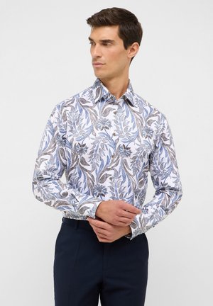 Witte overhemd met een blauw en bruin bloemenpatroon, lange mouwen, button-down kraag en contrasterende knopen. In combinatie met donkere broeken.