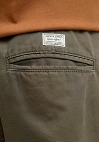 Hall hall materiaaliga kangas, millel on sile tekstuur, tagaküljel on tasku ja silt, kus on kirjas "JACK & JONES Superior Apparel."