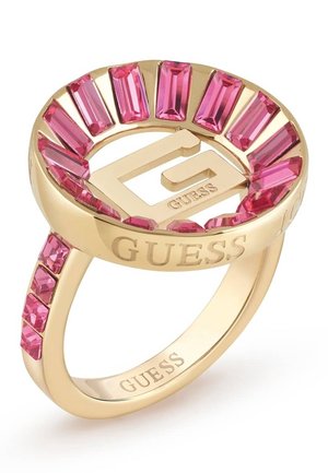 Vergulde Guess-ring met roze rechthoekige kristallen rondom een verhoogd "G"-logo, gegraveerd met "GUESS" op de band en de bovenrand.