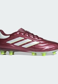 Botín de fútbol color burdeos con acentos en blanco y amarillo neón, diseño aerodinámico, superficie texturizada y seis tacos amarillos en la suela.