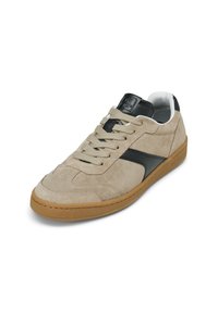 Baskets en daim beige avec des accents en cuir noir, bout rond, semelle en caoutchouc épaisse couleur tan, et lacets plats. Comprend un logo sur la languette.