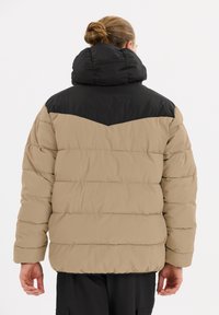 Puffjacka med en beige kropp och svart övre del, med hög krage, vadderad textur och horisontell sömnad.