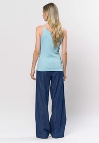 Šviesiai mėlynas ribuotas tanko viršus su plonomis petnešėlėmis, derinamas su laisvai priglundančiomis tamsaus džinso kelnėmis. Paprastas dizainas, lygi tekstūra.