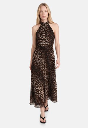 Kvinde iført en ærmeløs midi-kjole med leopardprint og halterneck samt sorte sandaler med firkantet tå, gående mod en ensfarvet baggrund.