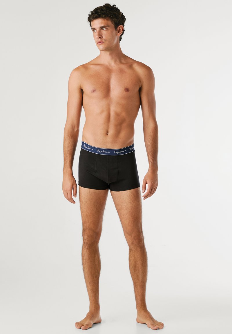Schwarze Boxershorts mit einem marineblauen Gummibund, der ein weißes Markenlogo zeigt. Der Stoff scheint weich und elastisch zu sein, und ist auf Komfort ausgelegt.