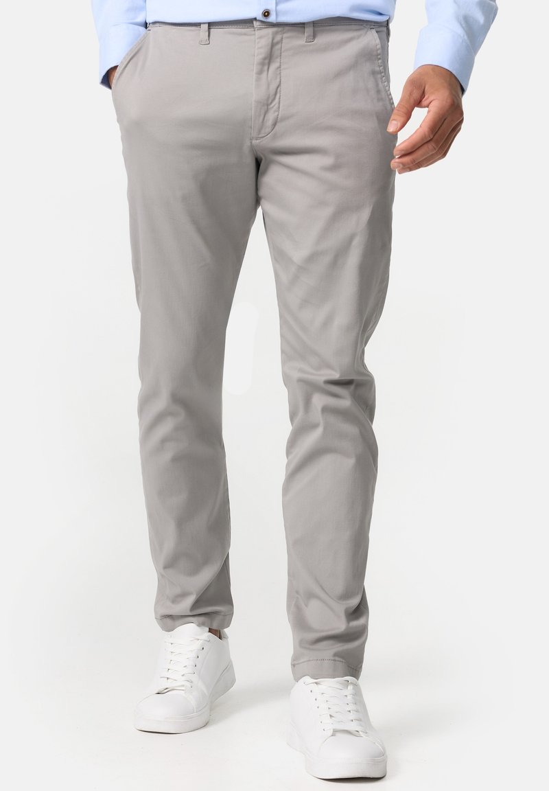 Grijze katoenen broek met een slim fit, voorzien van zijzakken en een knoopsluiting, gecombineerd met witte sneakers. Glad textuur.