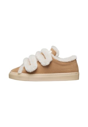 Sneaker in suede beige con cinturini in ecopelliccia bianca, punta arrotondata e suola in gomma. Il lato presenta un dettaglio con logo.