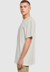 Lichtgrijze katoenen T-shirt met een relaxte pasvorm, korte mouwen en een ronde hals. Soepele textuur, eenvoudig ontwerp zonder zichtbare branding.