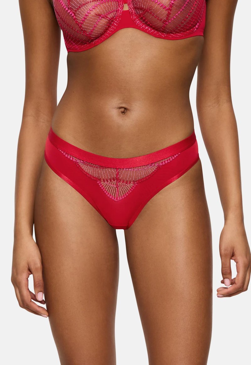 Heup-en-onder aanzicht van een vrouw in een rode kanten lingerieset met roze borduursels op de beha en bijpassende slipjes.