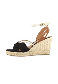 Black fabric wedge sandal with knotted detail, metallic accents, tan ankle strap, and jute-wrapped heel. Open-toe design.