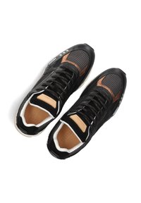 Zwarte sneakers met een combinatie van mesh en suede materialen, met een bruine accent, textuurdetails en een witte zool.