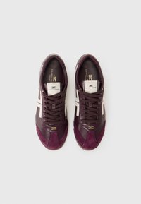 Maroon sneakers with leather and suede material, featuring white stripes, textured accents, and a gold logo on the tongue.