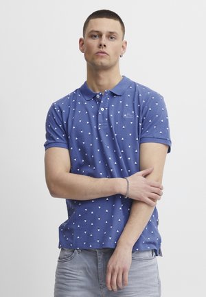 Mörkblå polo t-shirt med vitt triangelmönster, korta ärmar och krage. Har logotypbroderi på bröstet.