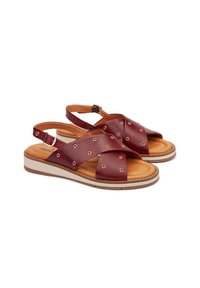 Sandalias de cuero marrón con correas entrelazadas y recortes circulares. Plantilla acolchada, suela de color claro y correa de tobillo ajustable.