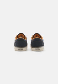 Navy suede sneakers with orange accents, featuring a high back and beige rubber sole. Marked with "etnies" on the heel.