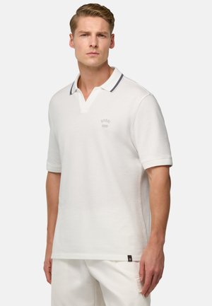 Weißes Polohemd mit kurzem Kragen, ausgestattet mit einem marineblauen Akzent und einem hellen gestickten Markenlogo. Aus weichem Baumwollmaterial, lässiger Schnitt.