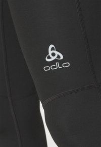 Black athletic long-sleeve top with Odlo logo. Features smooth texture, fitted design, and contrasting stitching.