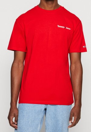 Czerwona bawełniana koszulka z krótkim rękawem, z białym logo "Tommy Jeans" na piersi oraz kontrastowym logo na rękawie.