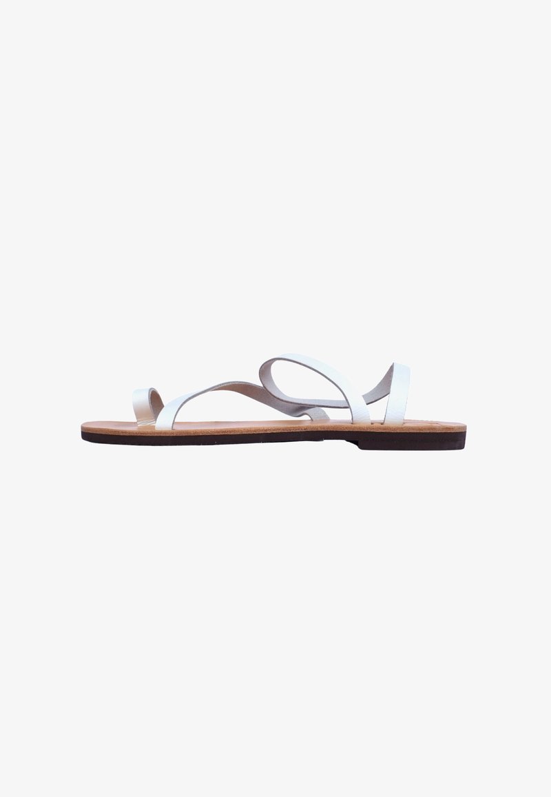 White leather sandals with two crossing straps, flat sole, and a natural cork insole. Minimalistic design with a smooth texture.