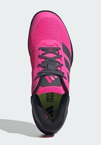 Φωτεινό ροζ αθλητικό παπούτσι με μαύρες λεπτομέρειες, άνω μέρος από δίχτυ, χοντρή λαστιχένια σόλα, επίπεδα κορδόνια και ορατή λεπτομέρεια λογότυπου στη γλώσσα.