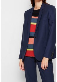 Marinblå blazer med strukturerade axlar, enknappsstängning och sidofickor, över en flerfärgad randig tröja. Skräddarsydd passform med slät textur.