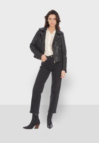 Black leather biker jacket with silver zippers, cream blouse, high-waisted black jeans, and black ankle boots with a wooden heel.
