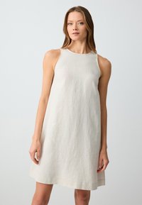 Helles Leinenkleid mit ärmellosem Schnitt, lockerer Silhouette, runder Ausschnitt und knielangem Saum. Minimalistische Textur und Details.