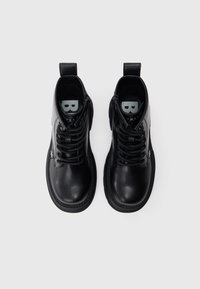Botas de tobillo de cuero negro con puntera redonda, diseño de cordones, acentos grises contrastantes y una lengüeta en la parte posterior.
