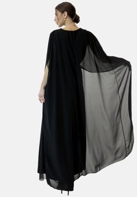 Robe cape en chiffon noir avec un design fluide, manches longues et ourlet dégradé, présentant une texture transparente et un drapé doux.