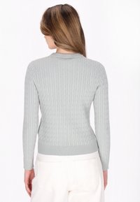 Maglione grigio chiaro lavorato a maglia con texture a coste, maniche lunghe e una vestibilità aderente. Presenta un collo rotondo e un orlo che si ferma sui fianchi.