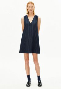 Marineblauwe mouwloze jurk met een V-hals, voorzien van verticale witte strepen, licht uitlopende silhouet en een gladde stoftextuur.