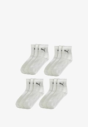 White athletic socks in a pack of four, featuring ribbed cuffs and black Puma logos on each sock. Smooth texture, standard crew length.
