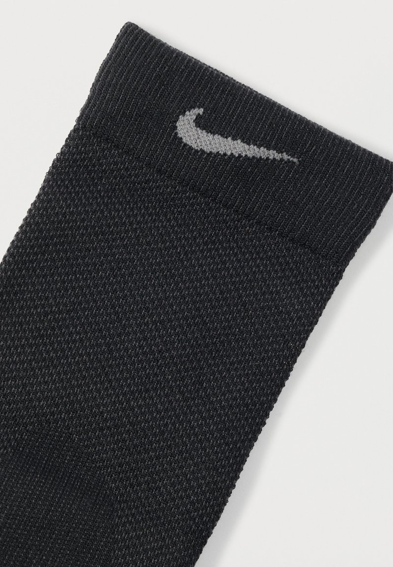 Calzino sportivo nero in tessuto testurizzato, con cima lavorata a maglia e logo Nike grigio sul polsino.