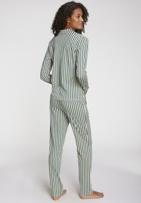 Striped pajama set in green and cream, featuring long sleeves, a collared design, and tapered pants with a relaxed fit. Soft, smooth fabric.