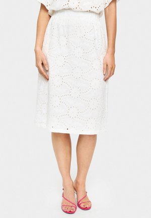Witte midi rok met bloemenborduursels en gaatjesdetails, met een geraffineerde taille. Gecombineerd met roze sandaaltjes met bandjes.
