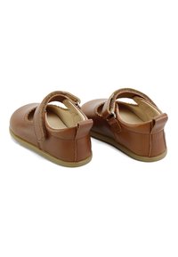 Zapatos de cuero marrón con punta redondeada, diseño recortado y una correa de Velcro. Suela de goma plana y forro suave para mayor comodidad.