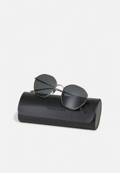 Ochelari de soare Giorgio Armani cu lentile negre octogonale, rame subțiri din metal argintiu, așezați pe un toc din piele mată neagră, embosat cu numele mărcii.