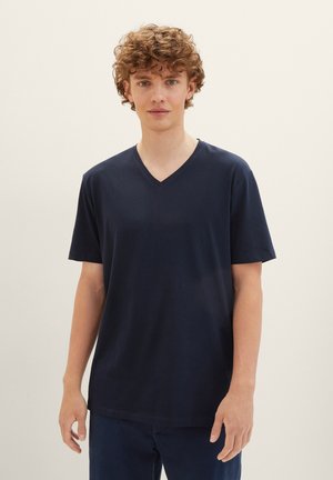 Tricou bleu marin cu guler în V, confecționat dintr-un material moale, cu mâneci scurte și o croială lejeră, având o textură fină și un design minimalist.