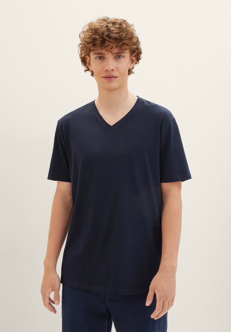 Tricou bleu marin cu guler în V, confecționat dintr-un material moale, cu mâneci scurte și o croială lejeră, având o textură fină și un design minimalist.
