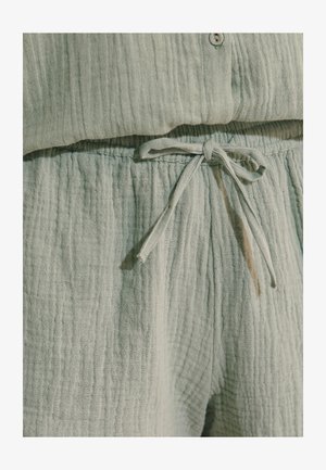 Pantalon vert clair en tissu texturé avec taille à cordon noué et top assorti avec un détail bouton au niveau de l'encolure.