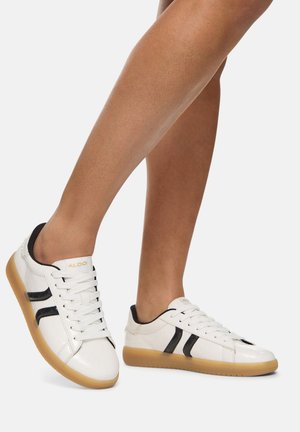 Sneaker bianche con strisce nere, tomaia in pelle liscia, suola in gomma e sei occhielli. Logo laterale.
