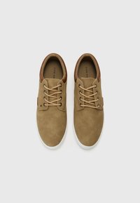 Brown suede shoes with a leather heel accent, featuring beige laces and a white rubber sole. Minimalist design with a smooth texture.