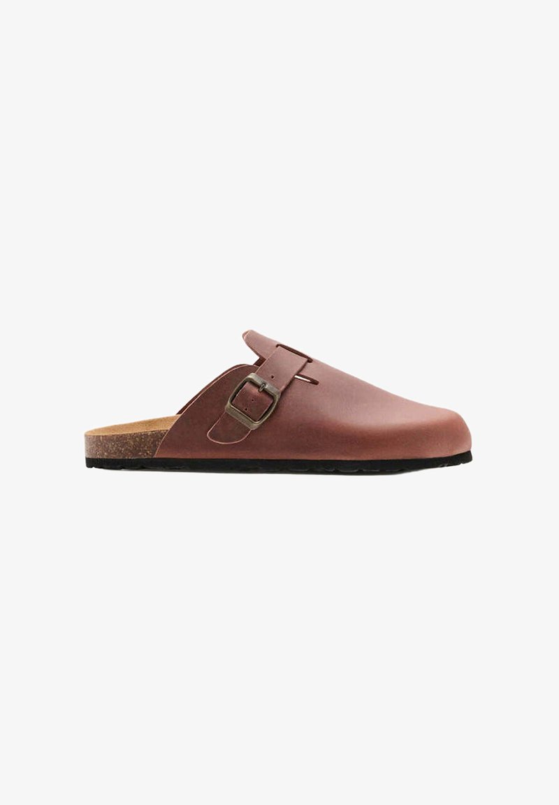 Sabot en cuir marron à enfiler avec une bride réglable à boucle et semelle en liège sur fond blanc.