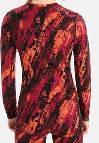 Pitkähihainen urheilupaita, jossa on monivärinen abstrakti kuvio punaisen, oranssin ja mustan sävyissä. Valmistettu joustavasta kankaasta, vartaloa myötäilevä malli.