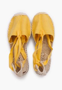 Espadrillas in tessuto giallo con punta tonda, nastri annodati e suola in juta intrecciata. Cuciture bianche che accentuano il bordo.