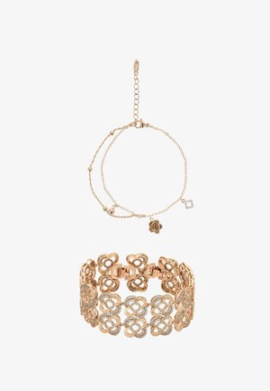 Delikatna złota bransoletka z małymi zawieszkami w kształcie kwiatów oraz szersza bransoletka typu mankiet ozdobiona mieniącymi się kryształkami.