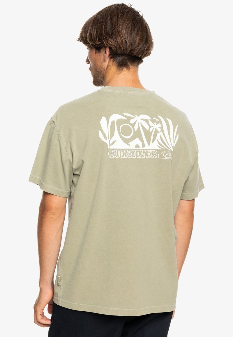 Olive green cotton T-shirt featuring a large white graphic on the back with tropical elements and the brand name "Quiksilver" below.