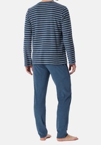Ensemble de vêtements de détente pour hommes comprenant un haut rayé bleu marine à manches longues et un pantalon uni bleu doux. Le tissu semble confortable et décontracté.
