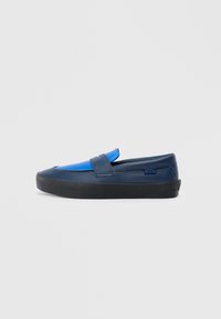 Modré a námořnické slip-on boty vyrobené z kůže s černou gumovou podrážkou, se strapcem přes vršek a minimálním brandingem.