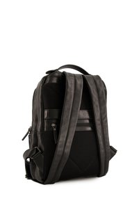Czarny plecak z gładką skórzaną powierzchnią, z siateczkowymi akcentami, zamykanymi przegrodami, wyściełanymi szelkami oraz usztywnioną konstrukcją.